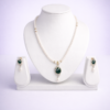 Gold-tone pearl necklace set with emerald green oval pendant and matching pearl drop earrings in flat-lay composition