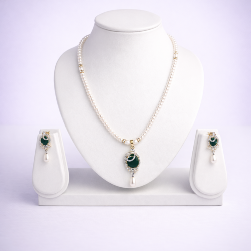 Gold-tone pearl necklace set with emerald green oval pendant and matching pearl drop earrings in flat-lay composition