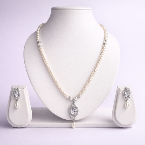 Silver-tone pearl necklace set with crystal oval pendant and matching pearl drop earrings displayed on white bust