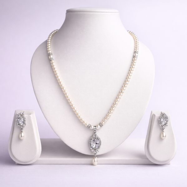 Silver-tone pearl necklace set with crystal oval pendant and matching pearl drop earrings displayed on white bust