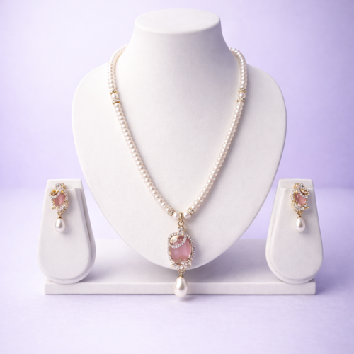Gold-tone pearl necklace set with rose pink oval pendant and matching pearl drop earrings in flat-lay composition