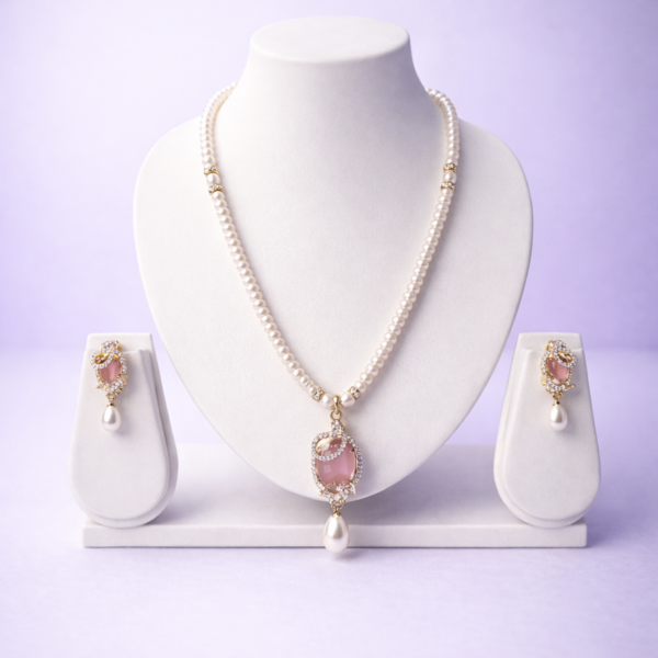 Gold-tone pearl necklace set with rose pink oval pendant and matching pearl drop earrings in flat-lay composition
