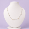 Silver-tone tin cup pearl station necklace with seven oval ivory pearls displayed on white bust against lavender background