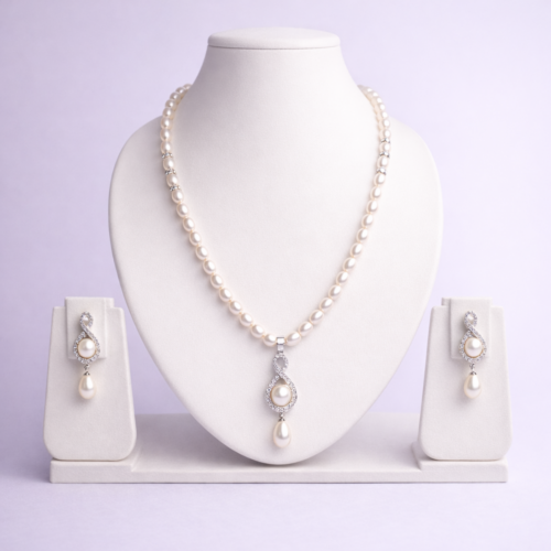 Silver-tone freshwater pearl necklace set with crystal infinity pendant and matching pearl drop dangle earrings on white bust