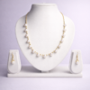 Gold-tone pearl station necklace set with evenly spaced round pearls and matching pearl drop earrings on white display bust