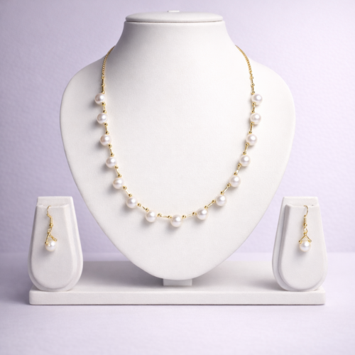 Gold-tone pearl station necklace set with evenly spaced round pearls and matching pearl drop earrings on white display bust